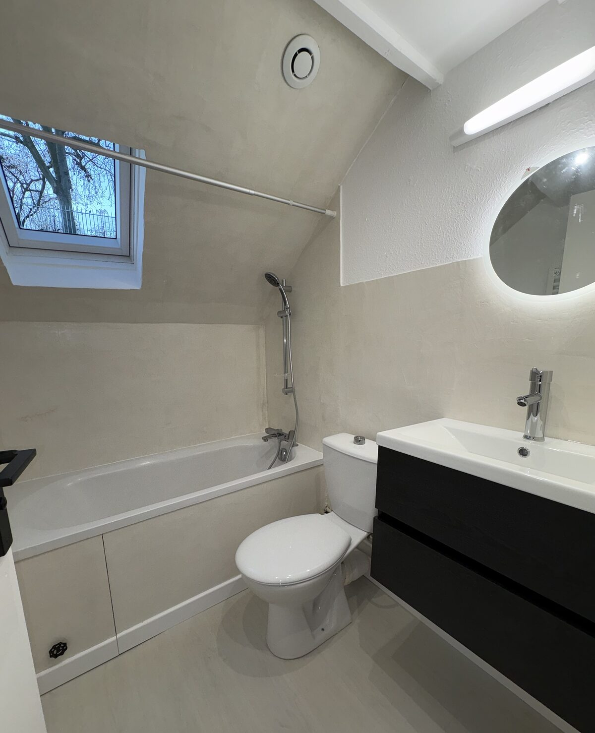 Salle de bain sous combles, meuble noir et miroir lumineux